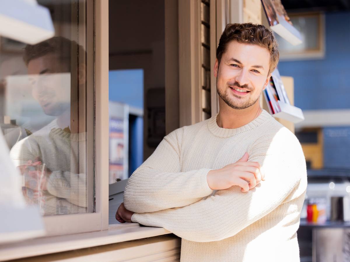 Nicolas posiert in einem cremefarbenen Pullover für die Kamera.