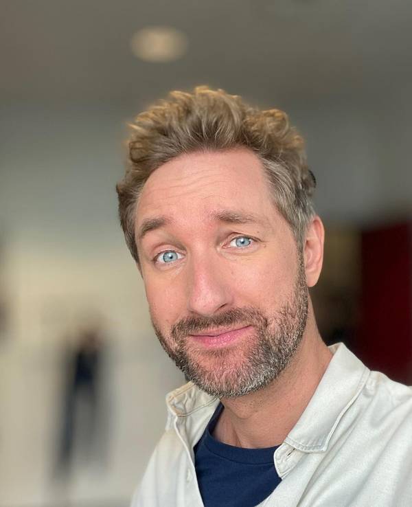Daniel posiert in einem beigen Hemd für ein Selfie.