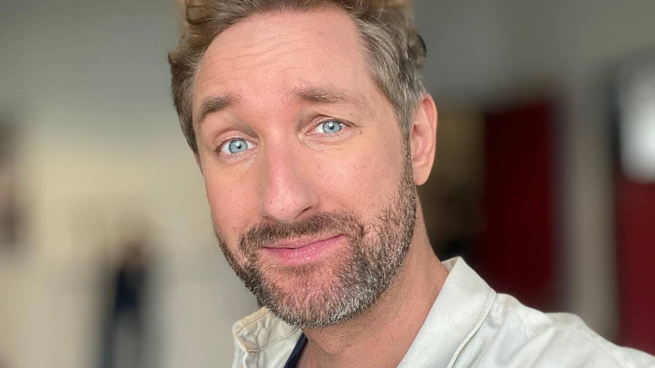Daniel posiert in einem beigen Hemd für ein Selfie.
