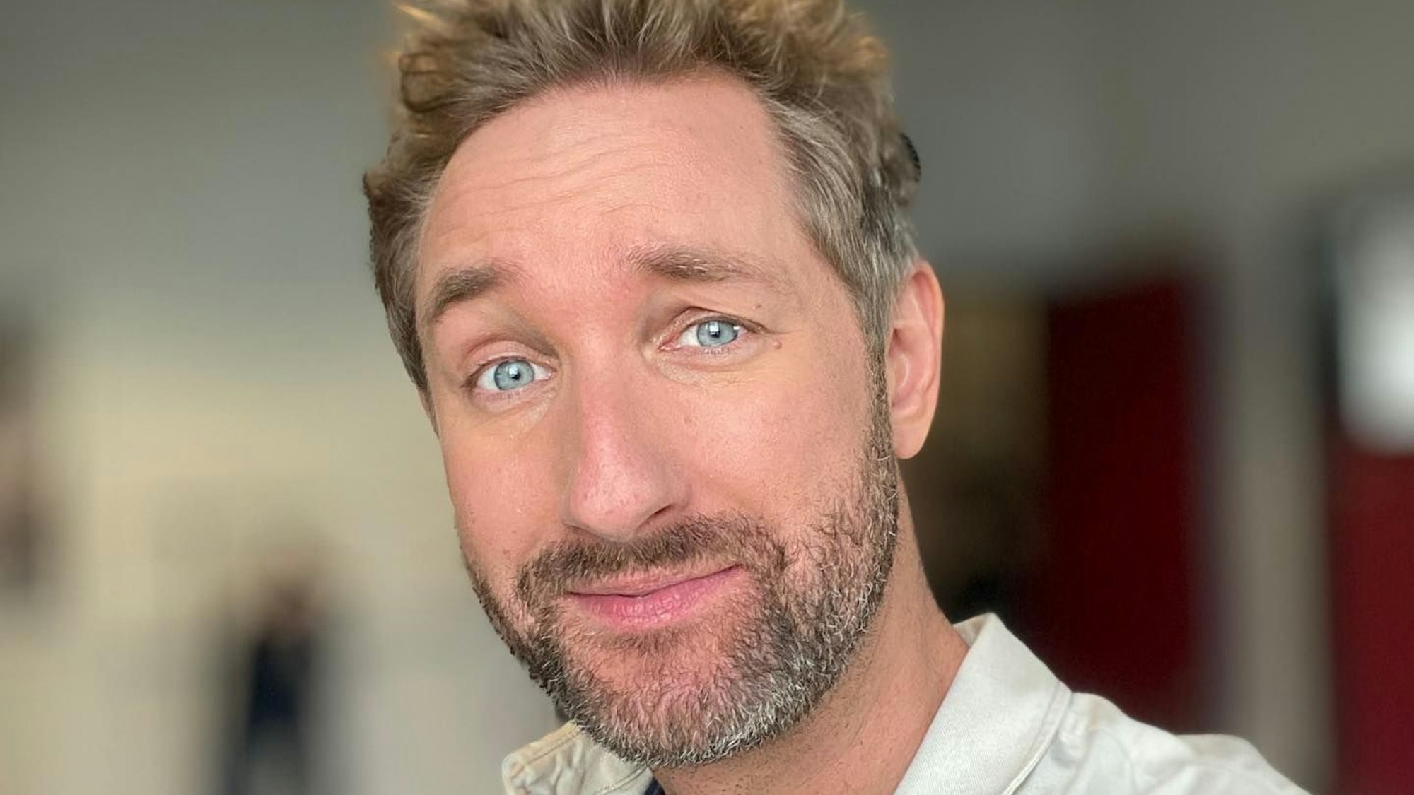 Daniel posiert in einem beigen Hemd für ein Selfie.