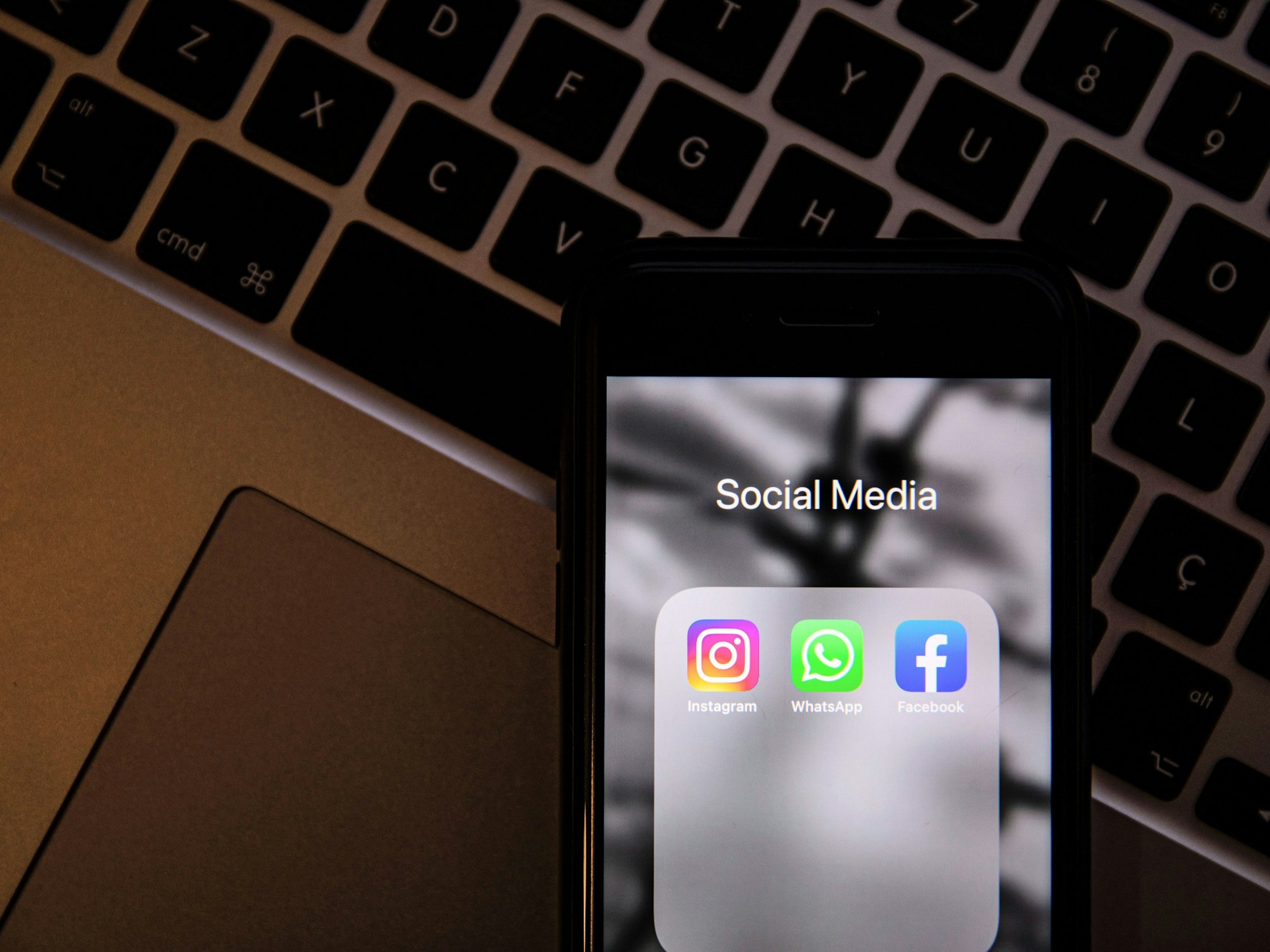 In dieser Fotoillustration sind die Logos von Instagram, Whatsapp und Facebook auf einem Smartphone-Bildschirm zu sehen. Im Hintergrund liegt eine Tastatur.