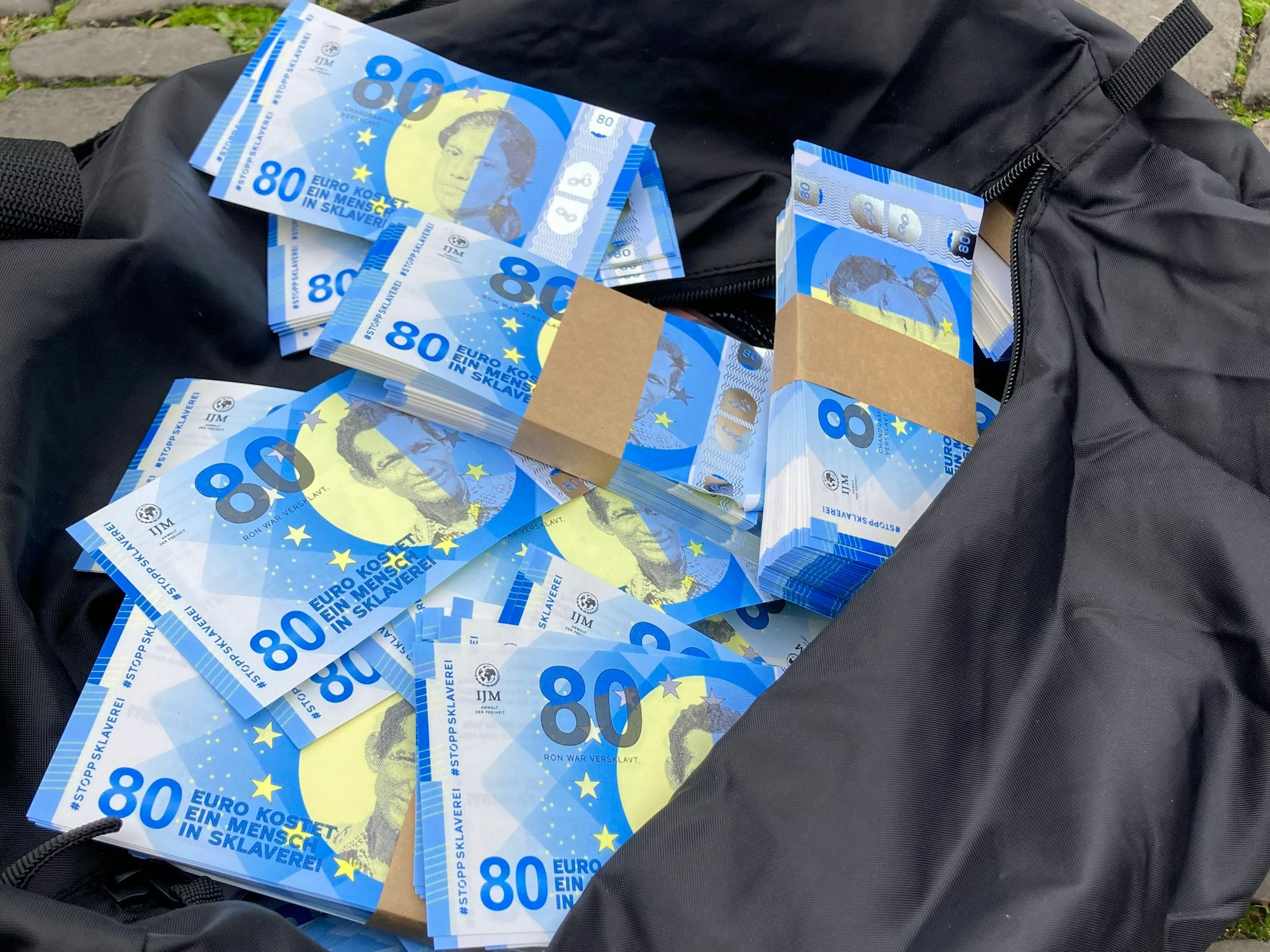 Mitglieder von International Justice Mission verteilten am 15. Oktober 2022 auf dem Alter Markt in Köln 80-Euro-Geldscheine, um auf moderne Sklaverei hinzuweisen.