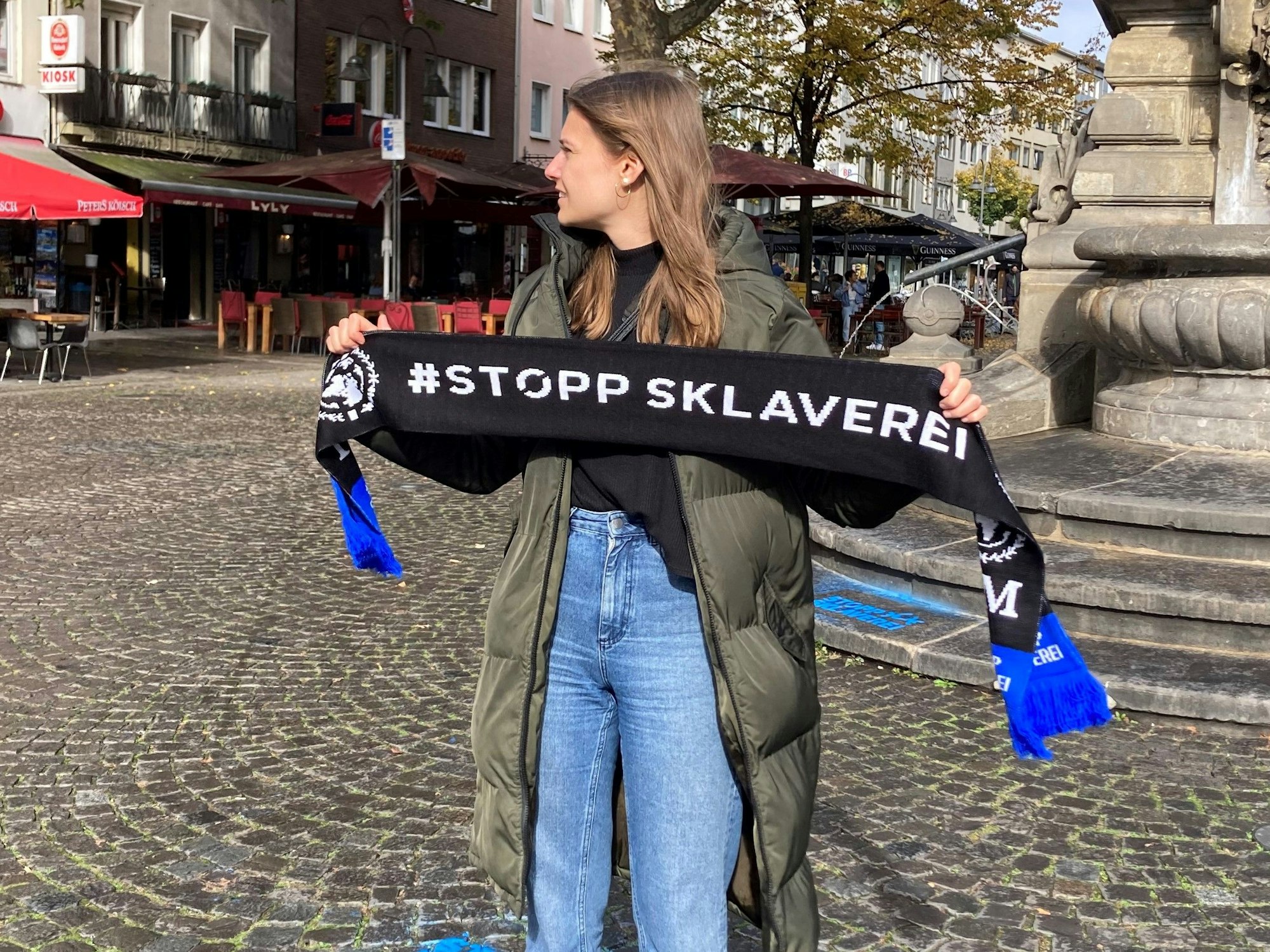 Eine Aktivistin International Justice Mission hält einen Schal mit der Aufschrift „Stopp Sklaverei“ hoch.