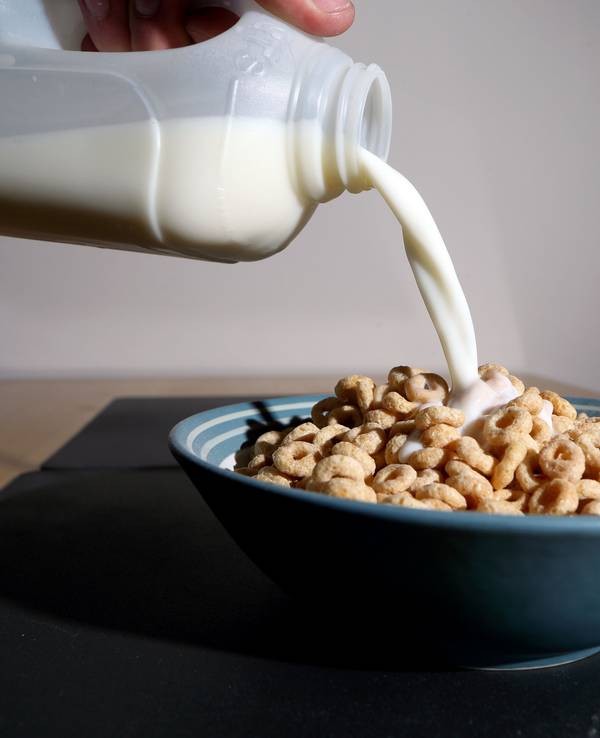 Milch wird in eine Schüssel mit Frühstückscerealien gegossen.