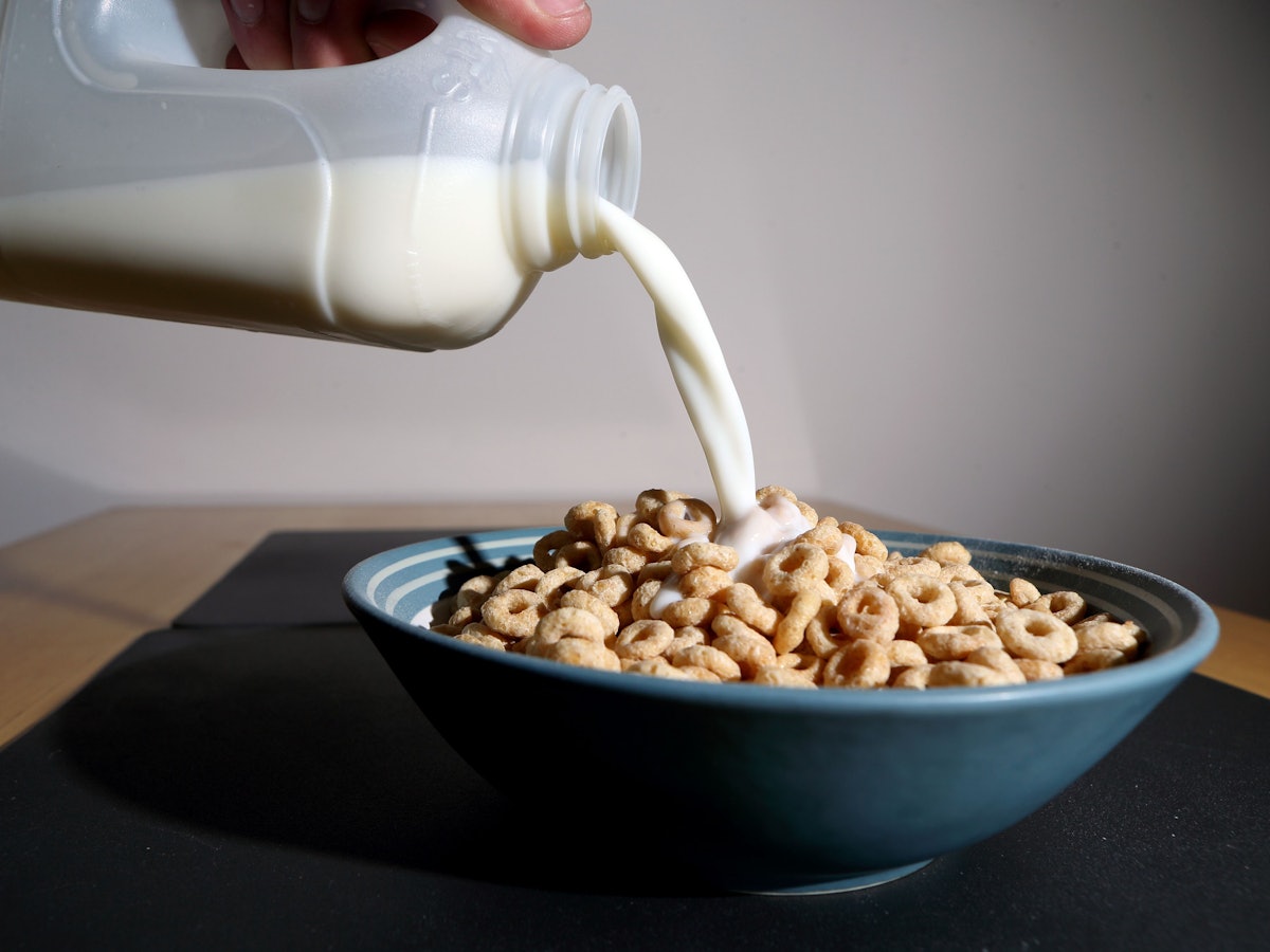Milch wird in eine Schüssel mit Frühstückscerealien gegossen.