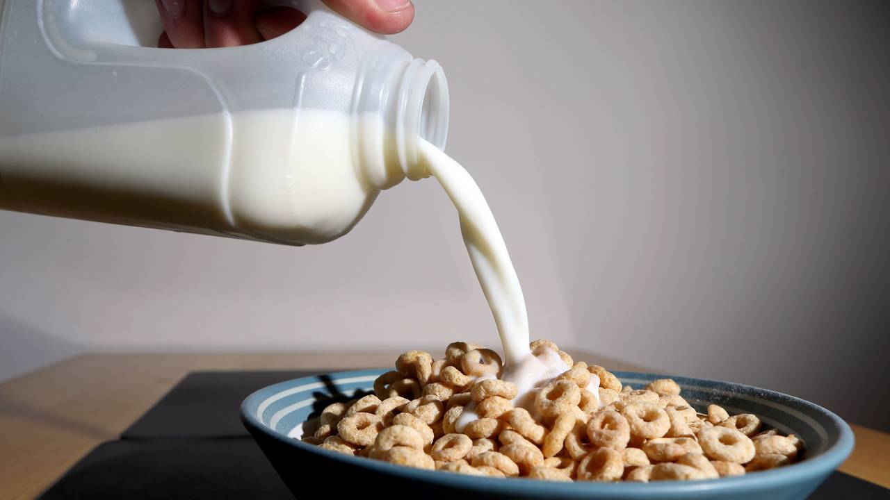 Milch wird in eine Schüssel mit Frühstückscerealien gegossen.