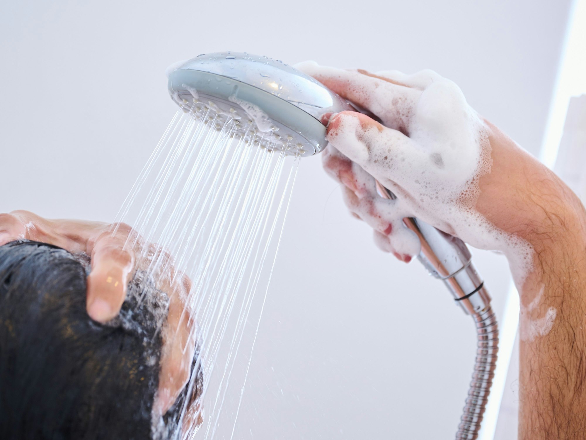 Ein Mann steht Zuhause in der Dusche und wäscht sich die Haare (gestellte Szene).
