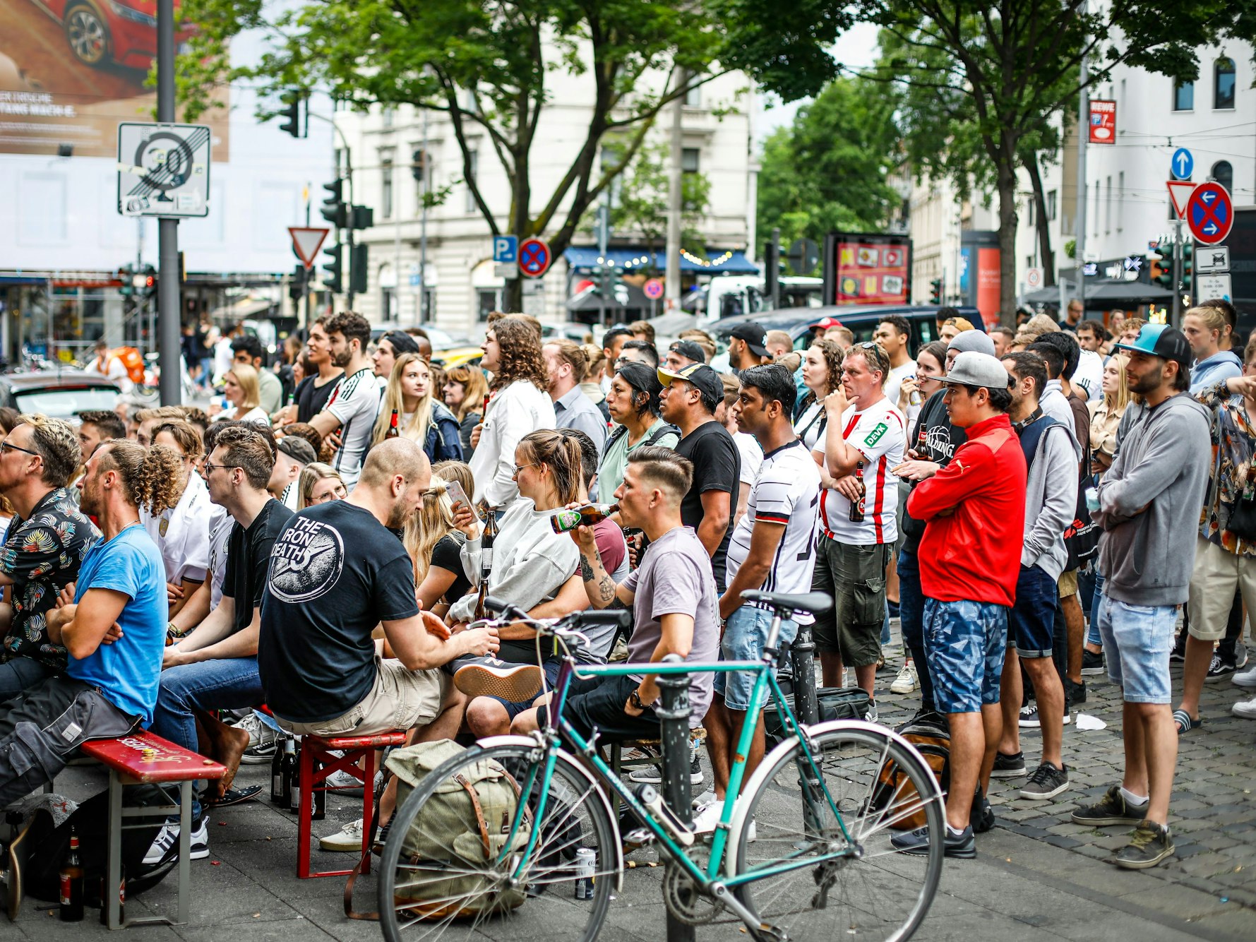 Fußballfans stehen während der Fußball-EM an einer Kneipe und verfolgen gemeinsam ein Spiel.
