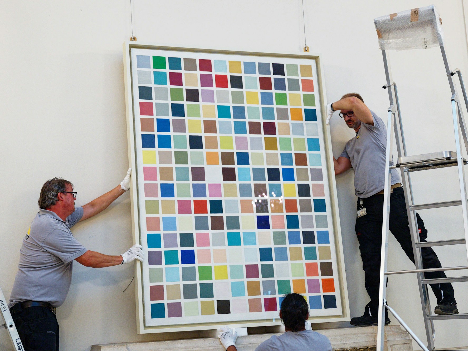 Mitarbeiter hängen das Werk 192 Farben von Gerhard Richter in einem Versteigerungshaus in Köln auf.