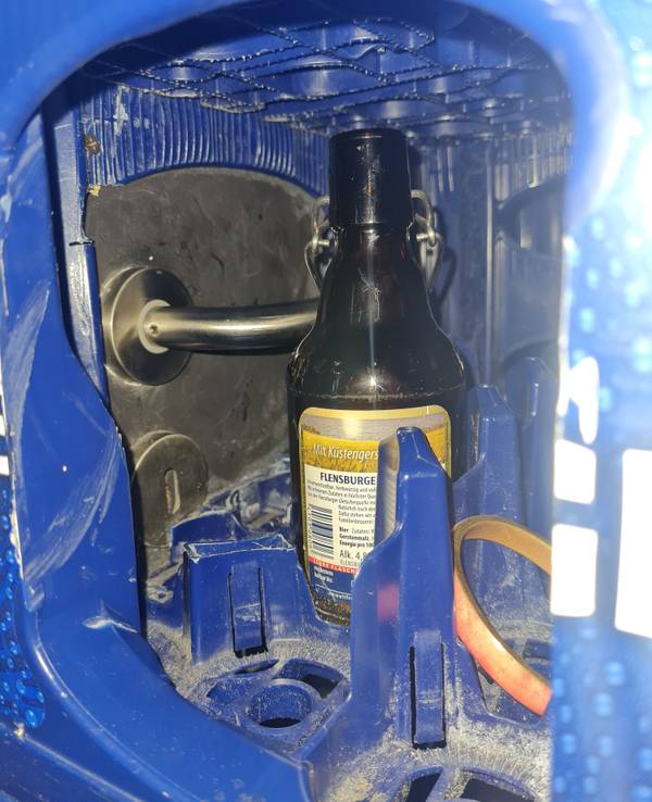 Ein Türgriff ist durch die Öffnung eines Bierkastens zu sehen.