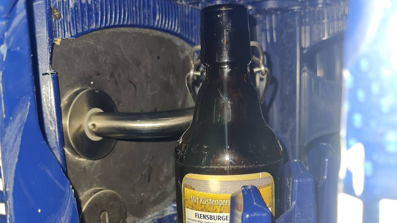 Ein Türgriff ist durch die Öffnung eines Bierkastens zu sehen.