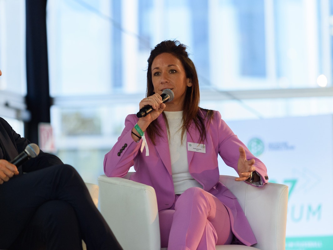 Nadine Kessler hält ein Mikrofon und spricht.