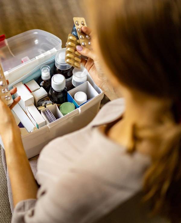 Person hat Tabletten in der Hand. Box mit Medikamenten und Verbandszeug. Bild für Amazon-Artikel.