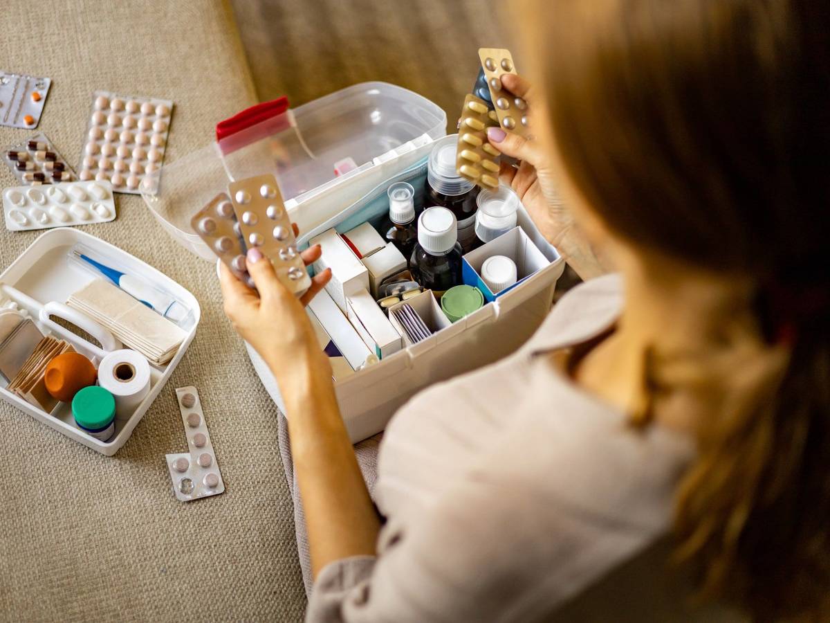 Person hat Tabletten in der Hand. Box mit Medikamenten und Verbandszeug. Bild für Amazon-Artikel.