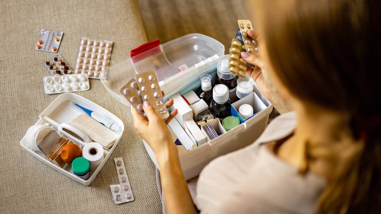 Person hat Tabletten in der Hand. Box mit Medikamenten und Verbandszeug. Bild für Amazon-Artikel.