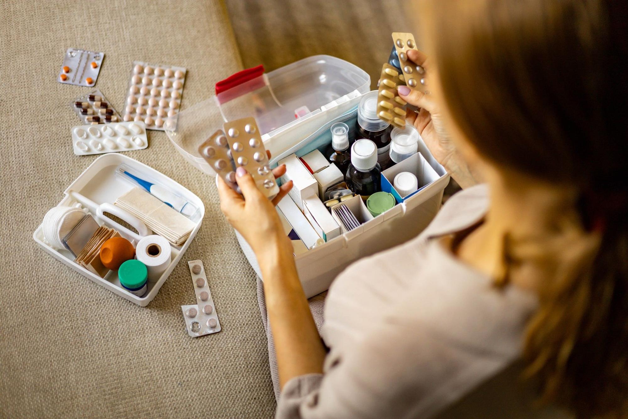 Person hat Tabletten in der Hand. Box mit Medikamenten und Verbandszeug. Bild für Amazon-Artikel.