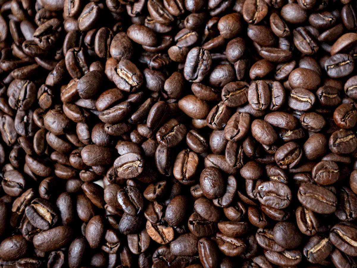 Geröstete Kaffeebohnen liegen auf einem Tisch.