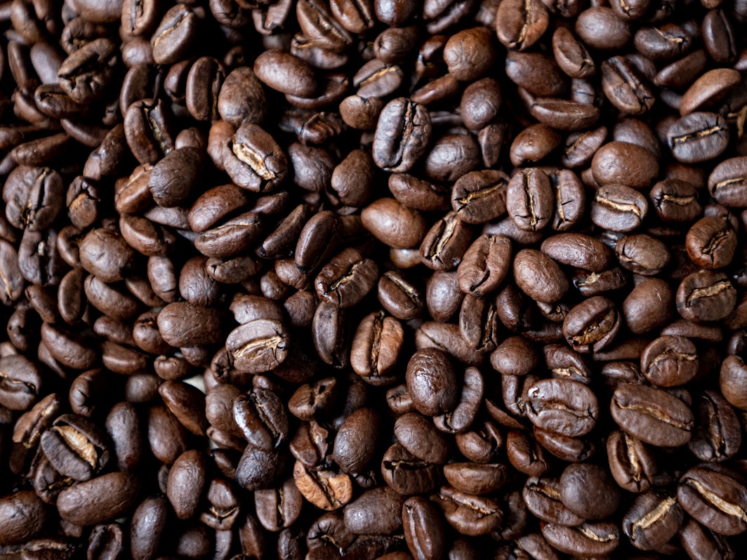 Geröstete Kaffeebohnen liegen auf einem Tisch.