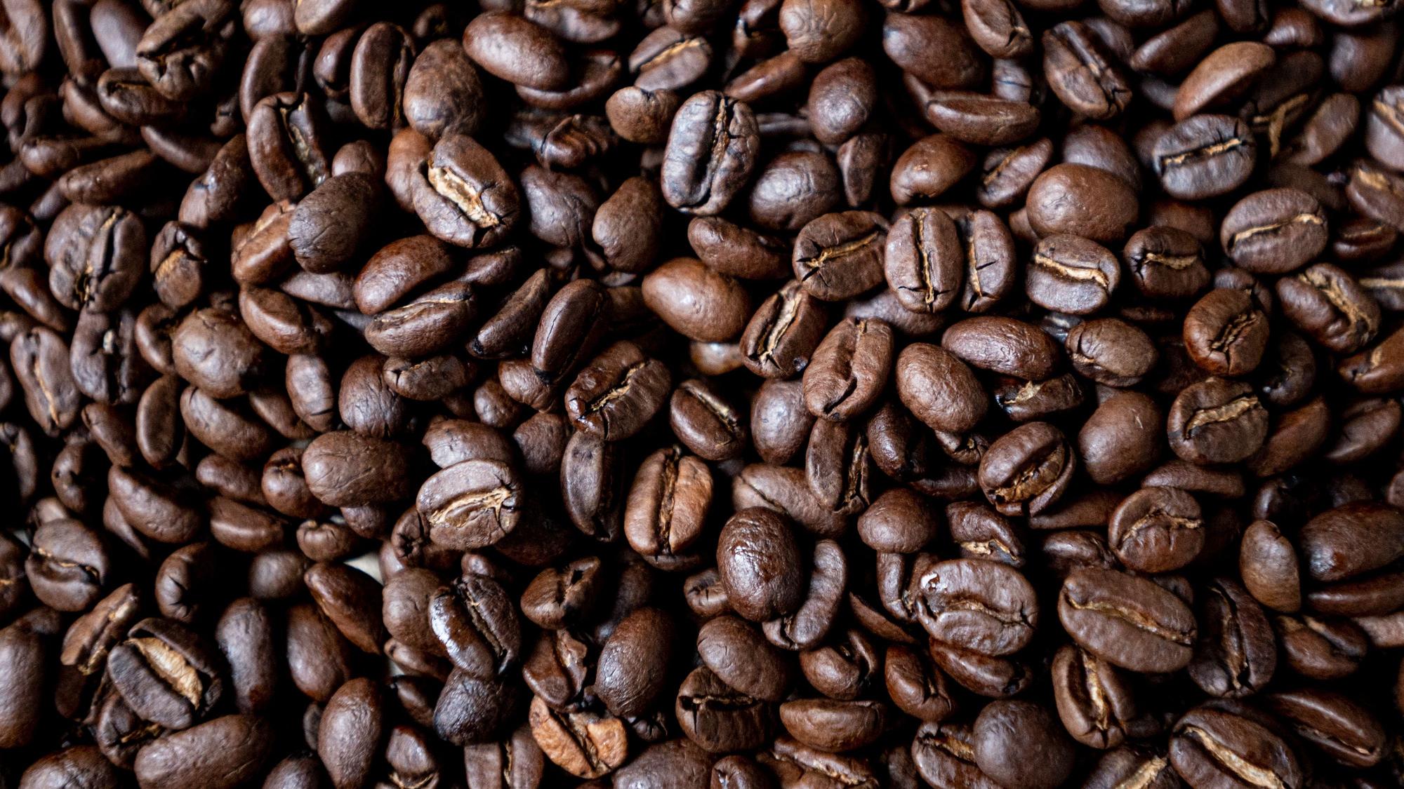 Geröstete Kaffeebohnen liegen auf einem Tisch.