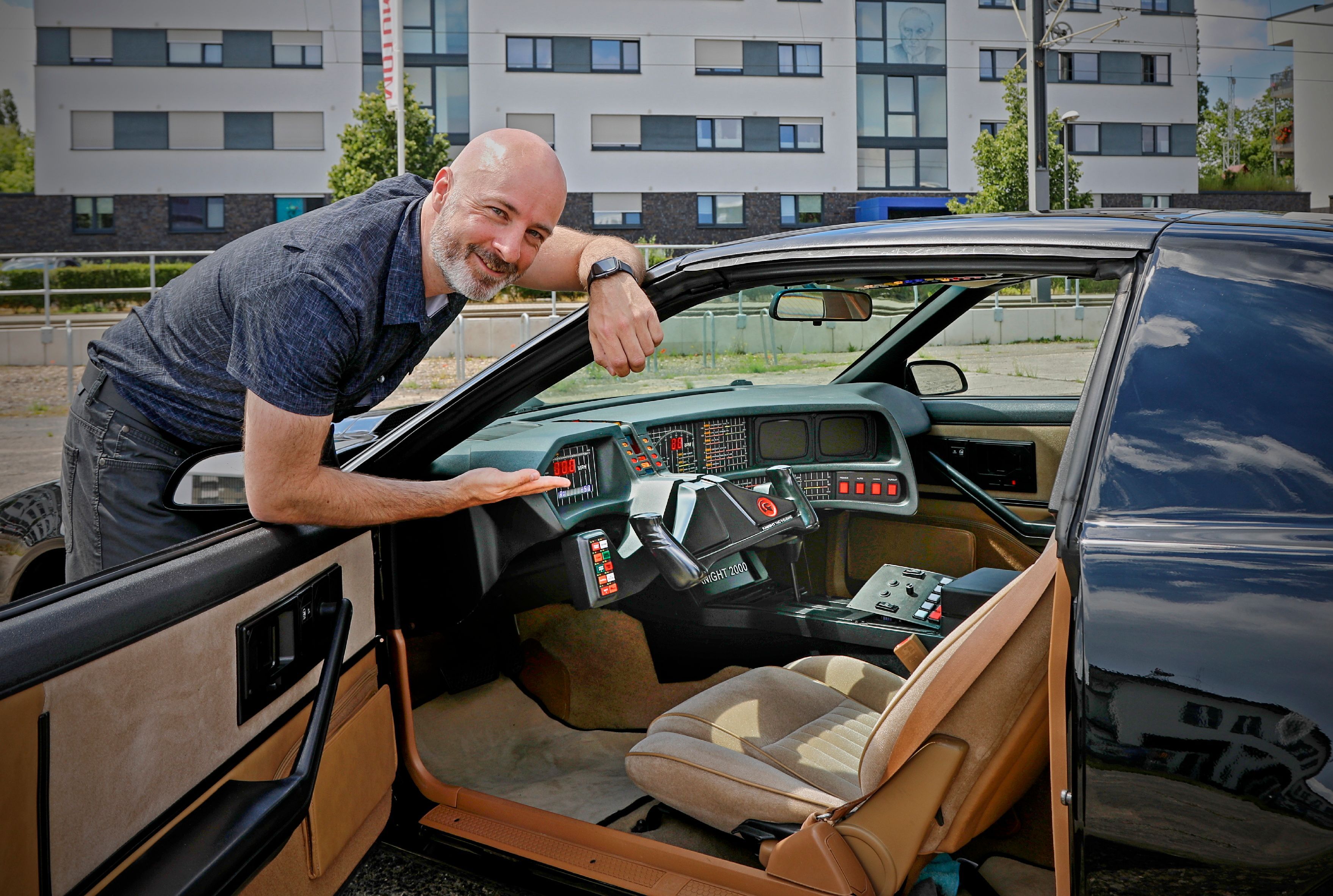 Christian Groeling lehnt an seinem Auto und zeigt hinein, um es zu präsentieren.