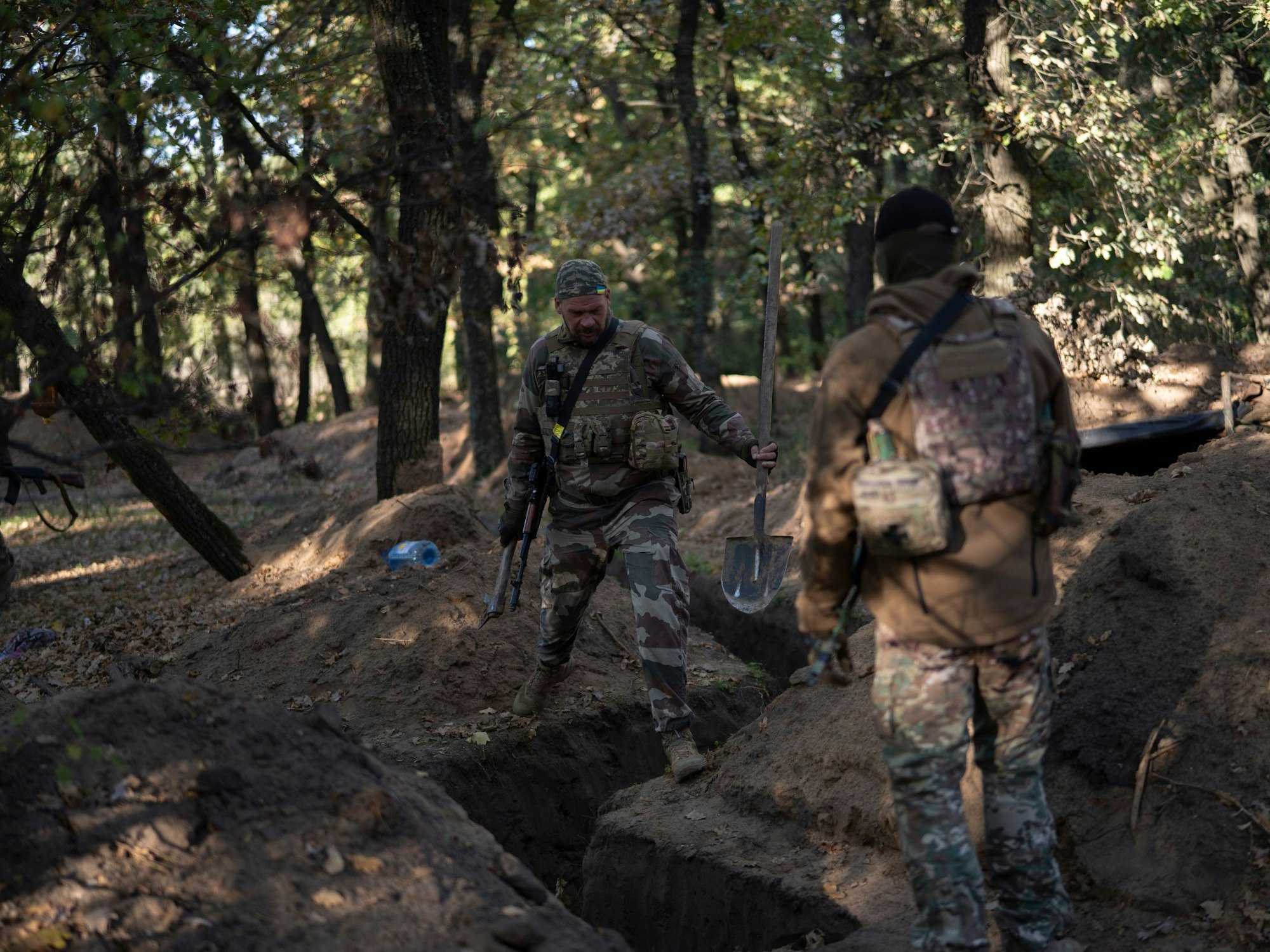 Ukrainische Soldaten überprüfen die von russischen Soldaten ausgehobenen Schützengräben.