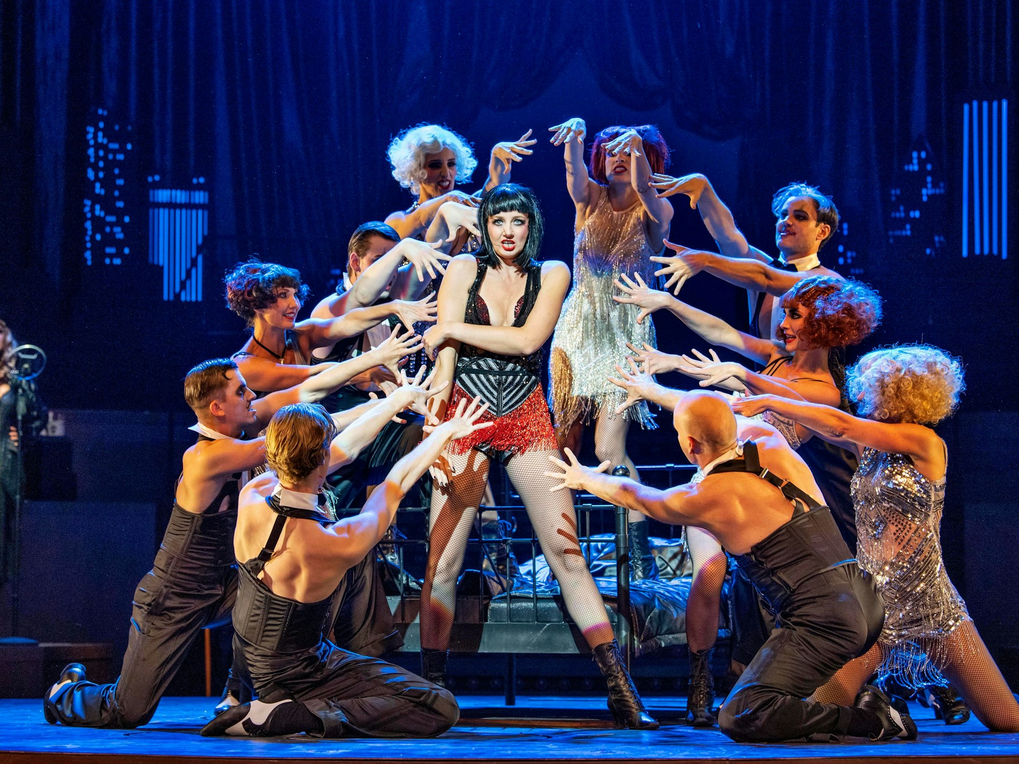 Bettina Mönch als Velma Kelly auf der Bühne umgeben von Tänzerinnen und Tänzern.