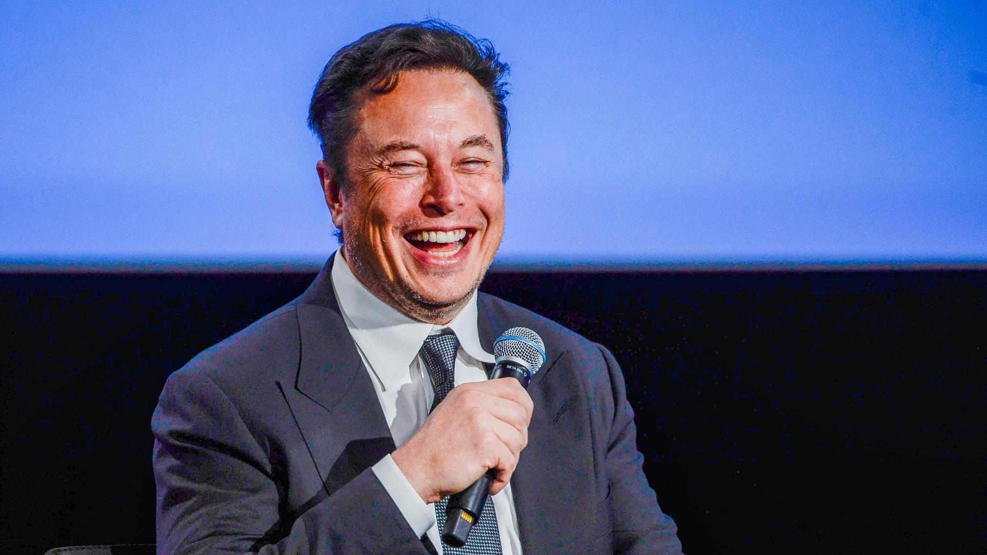 Elon Musk hält ein Mikro in der Hand.