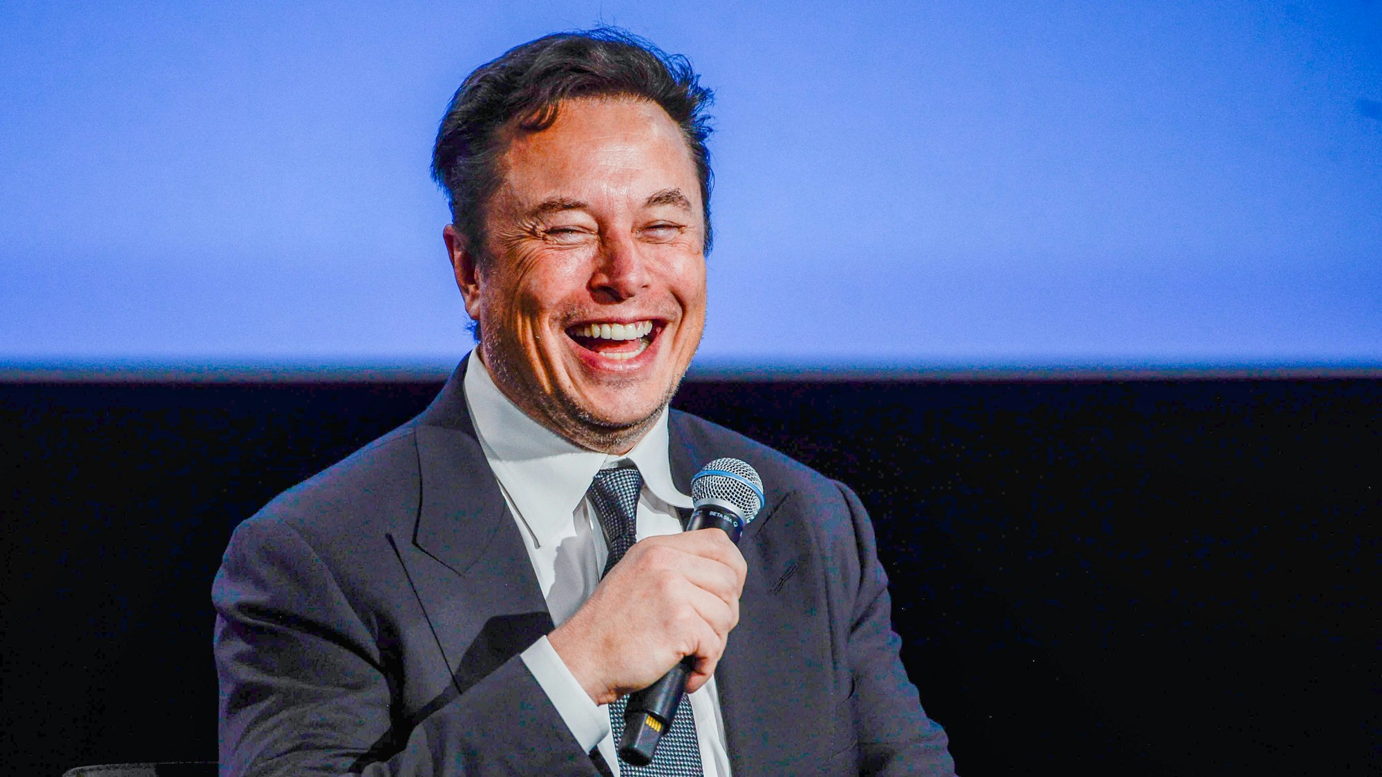 Elon Musk hält ein Mikro in der Hand.