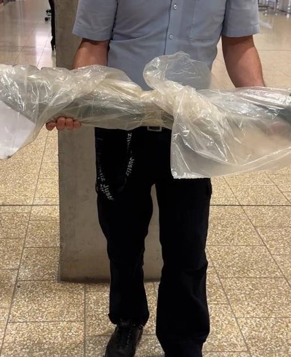 Ein Mann hält einen in Folie gewickelten Poller in den Händen.