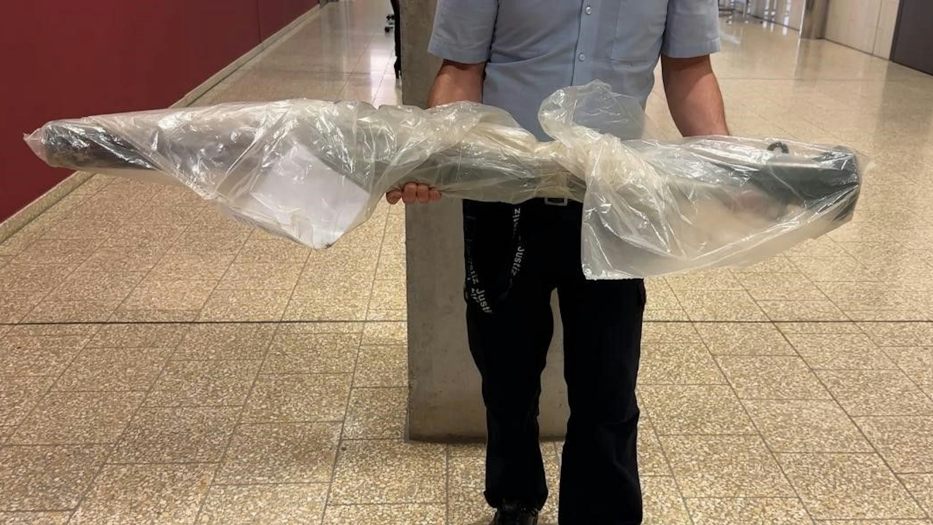 Ein Mann hält einen in Folie gewickelten Poller in den Händen.