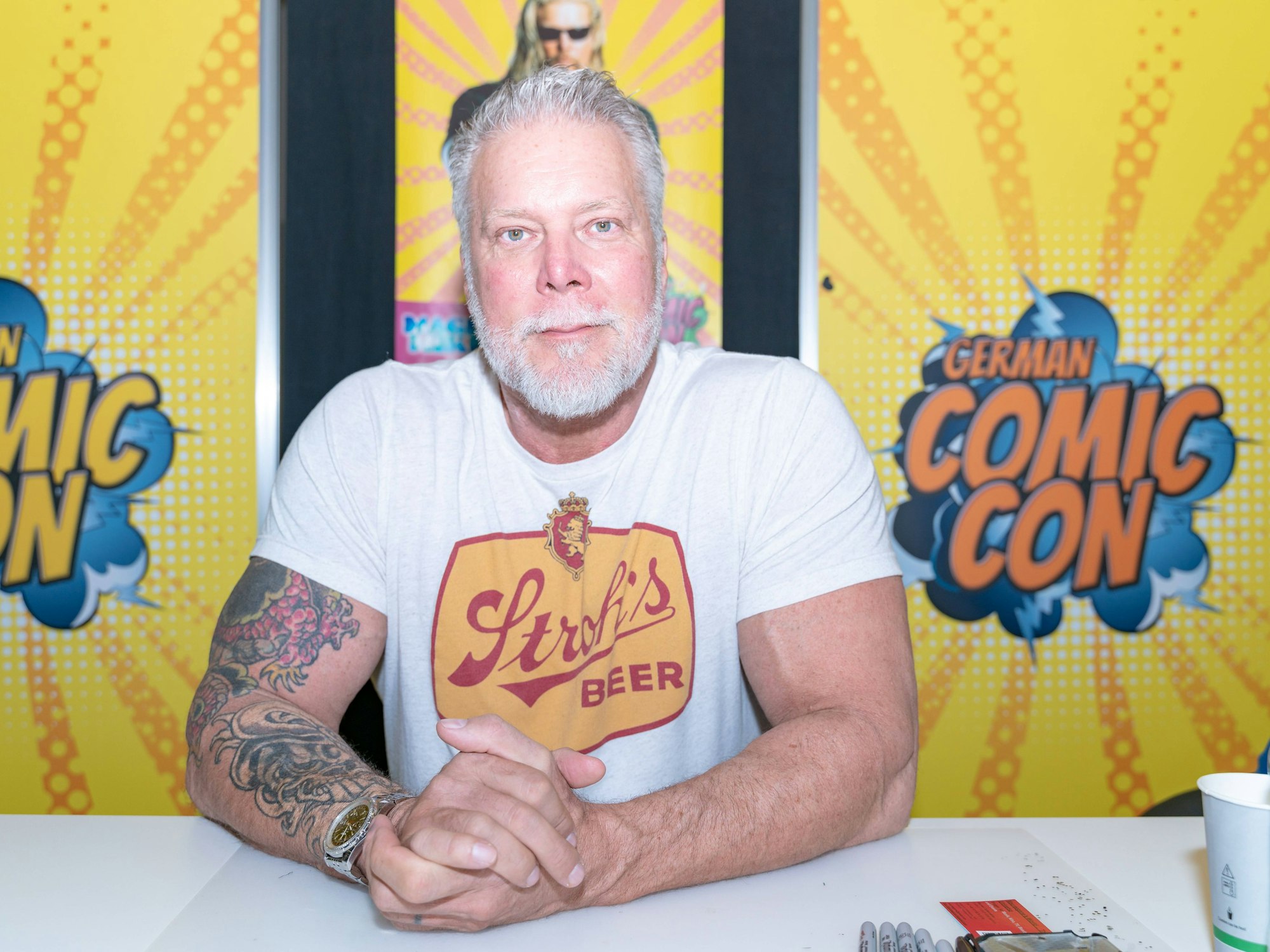 Kevin Nash sitzt bei einem Termin Dortmund am Tisch.