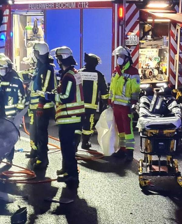 Rettungskräfte stehen neben einem stark beschädigten Auto.