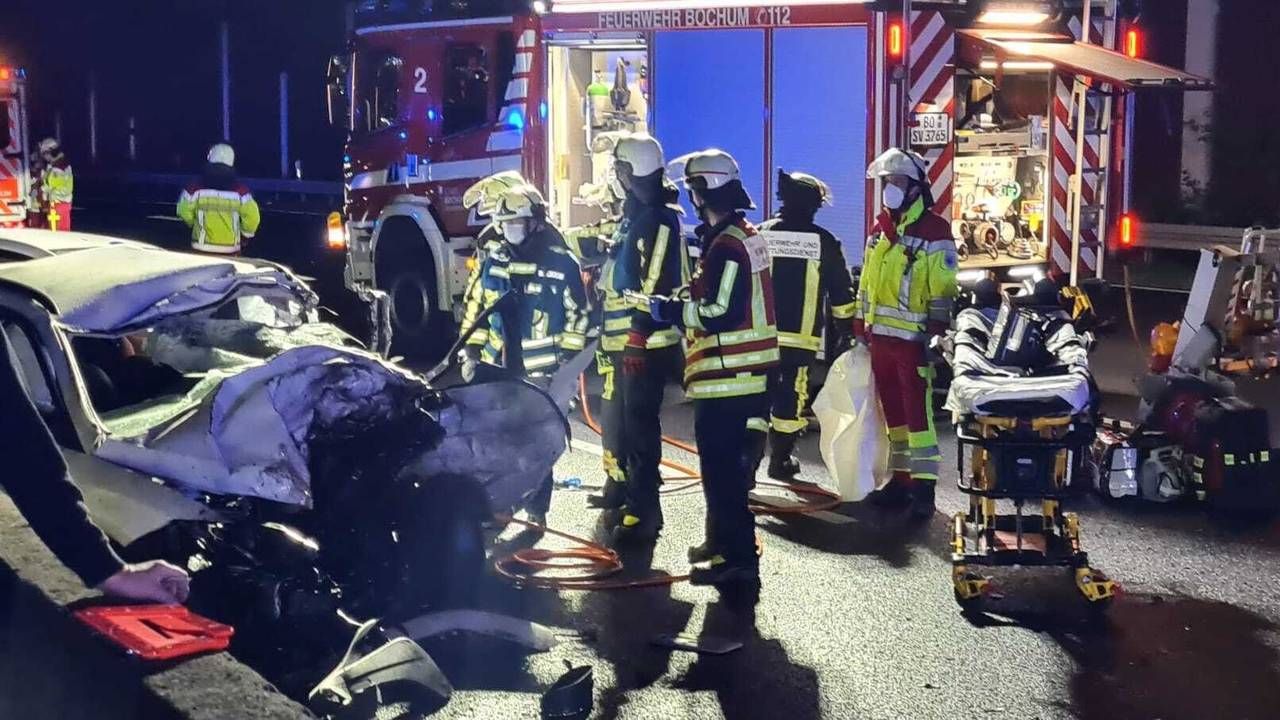 Rettungskräfte stehen neben einem stark beschädigten Auto.