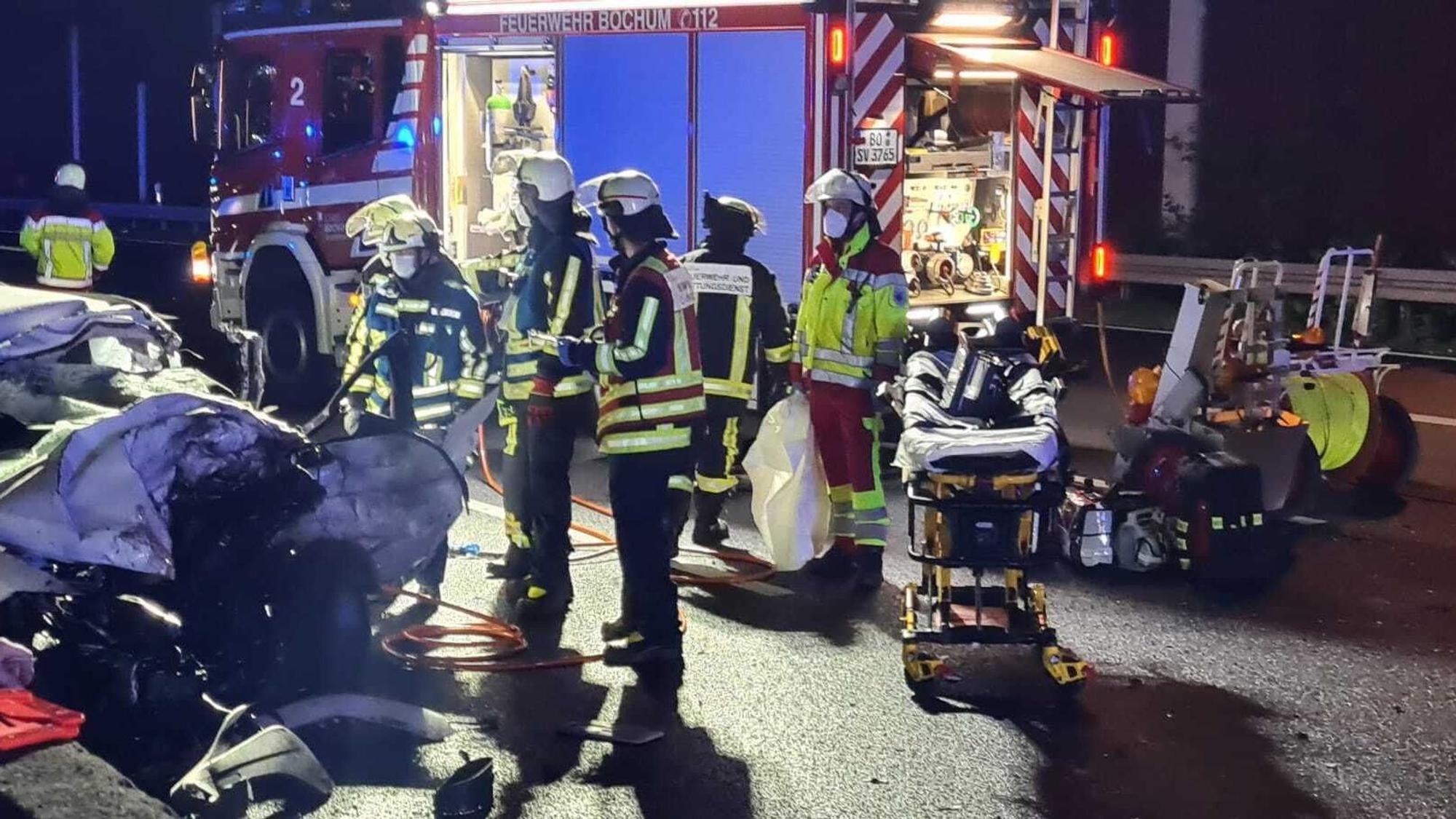Rettungskräfte stehen neben einem stark beschädigten Auto.