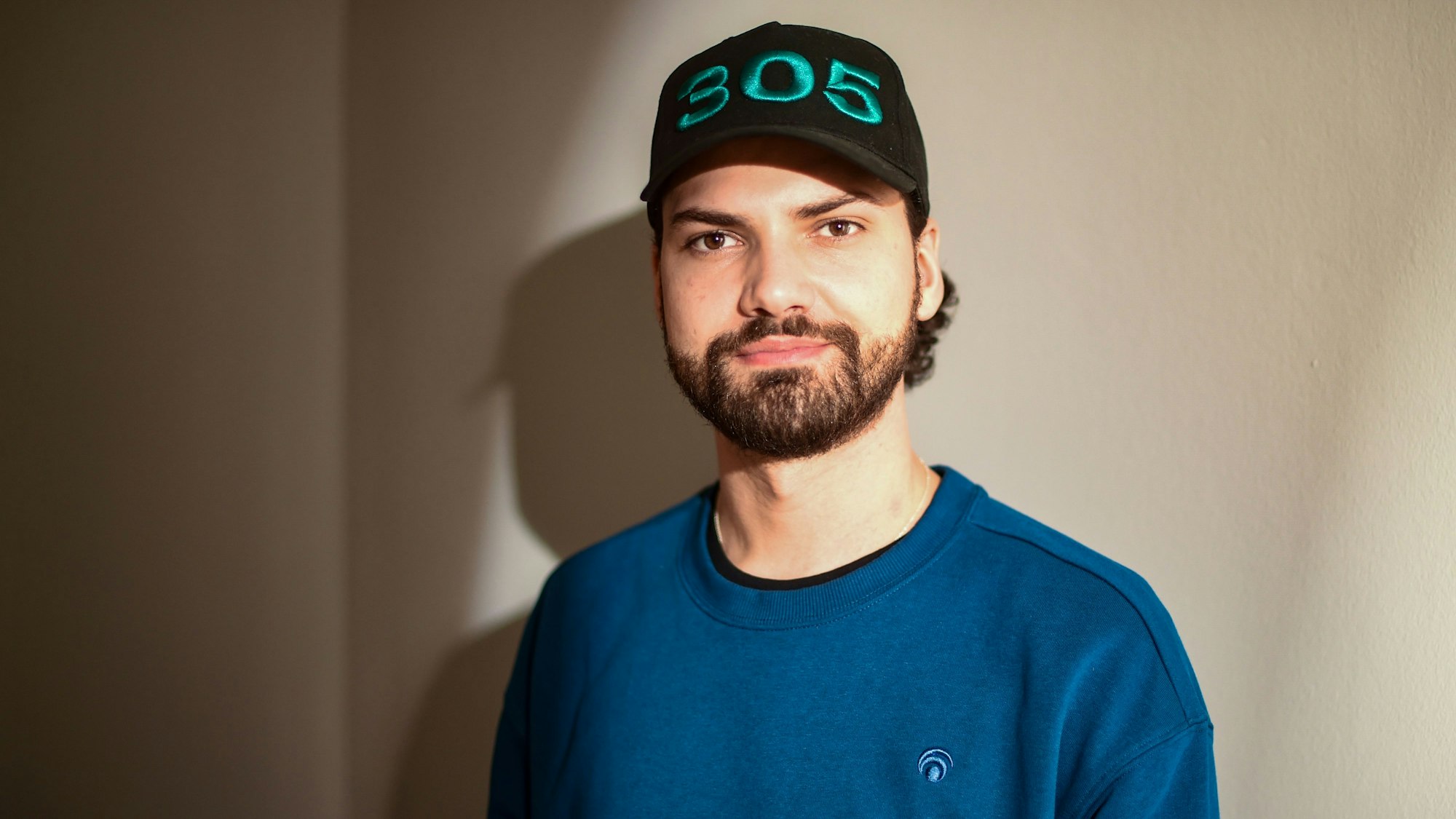 Jimi Blue Ochsenknecht posiert in blauem Pullover und Cap für die Kameras.