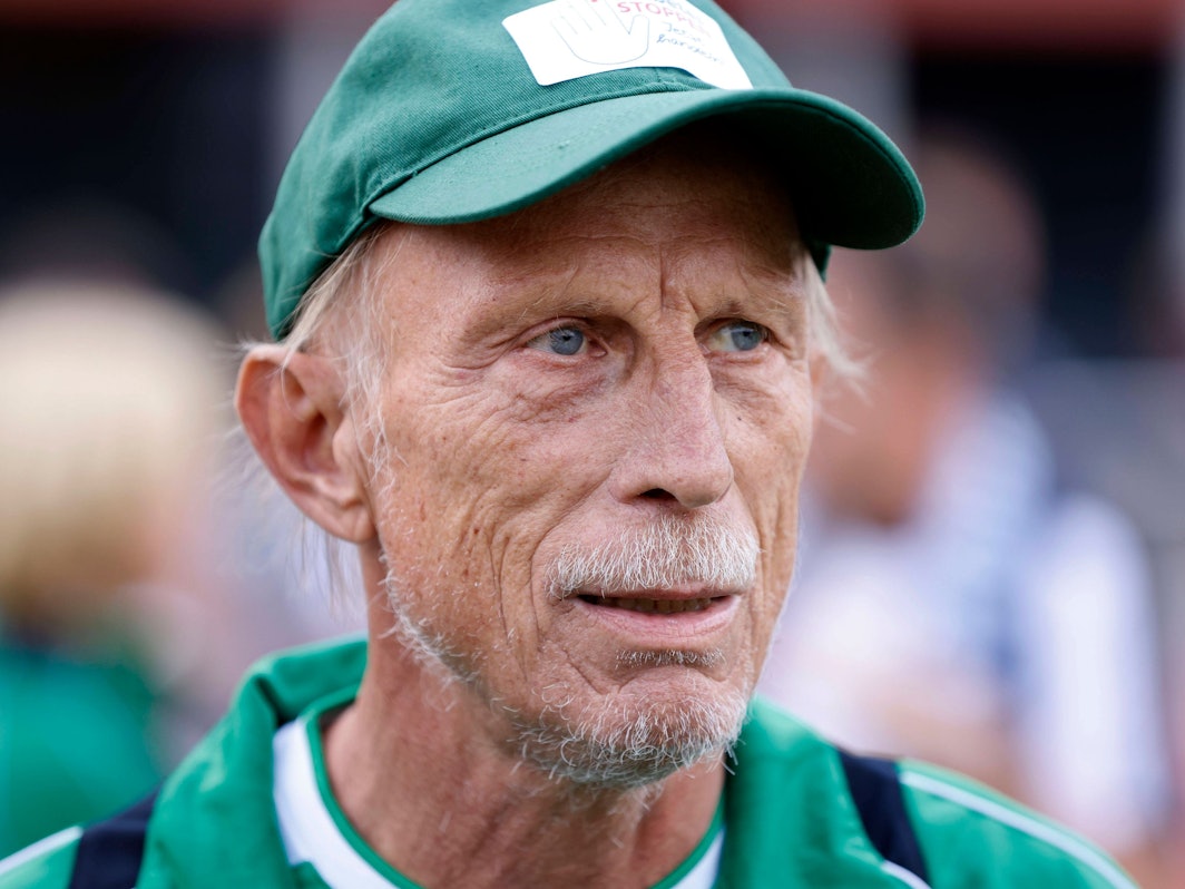 Christoph Daum steht mit Kappe am Spielfeldrand.