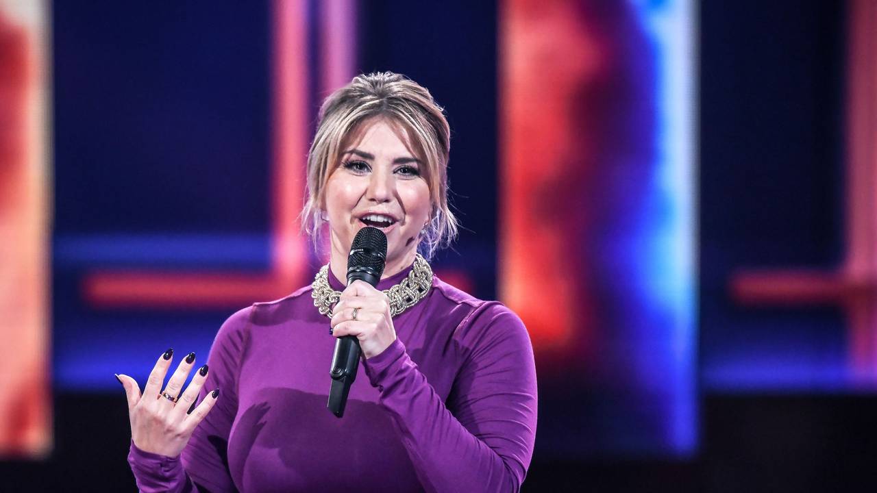 Beatrice Egli moderiert in einem lila Kleid auf der Bühne.