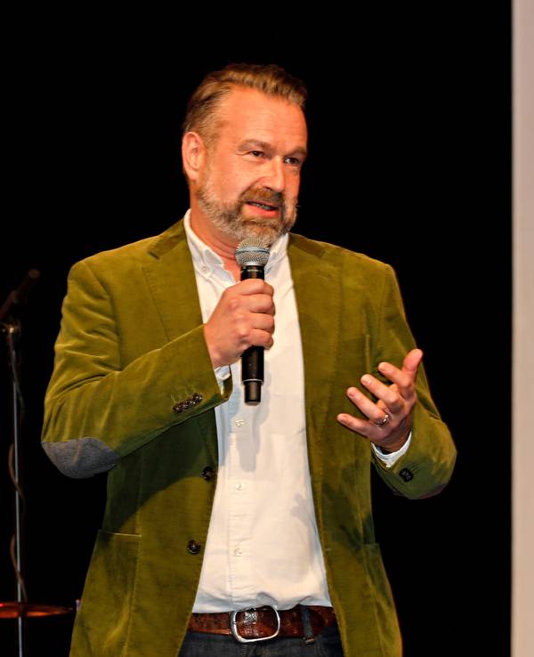 Volker Weininger steht mit einem Mikrofon auf der Bühne.