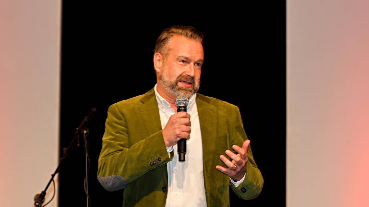 Volker Weininger steht mit einem Mikrofon auf der Bühne.