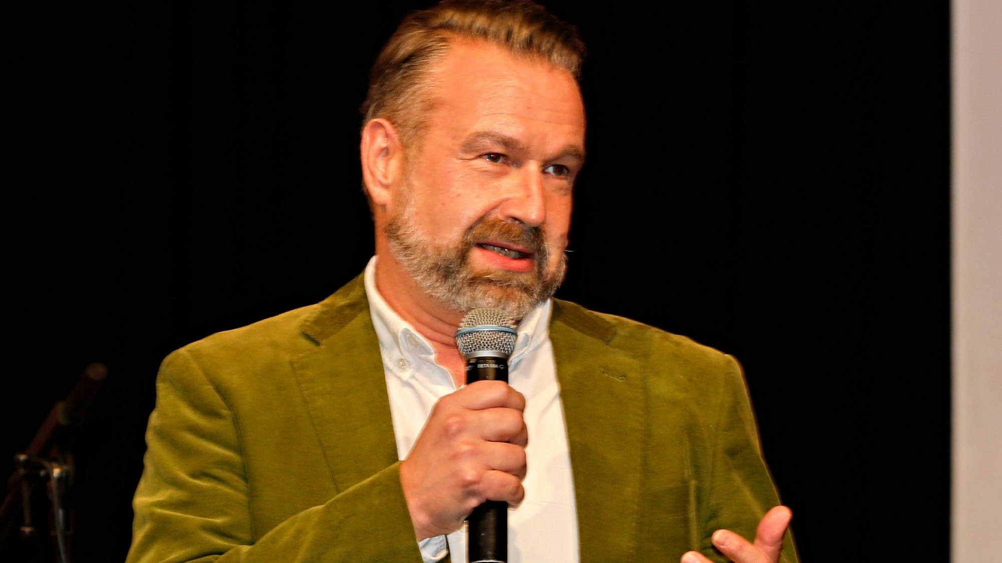 Volker Weininger steht mit einem Mikrofon auf der Bühne.