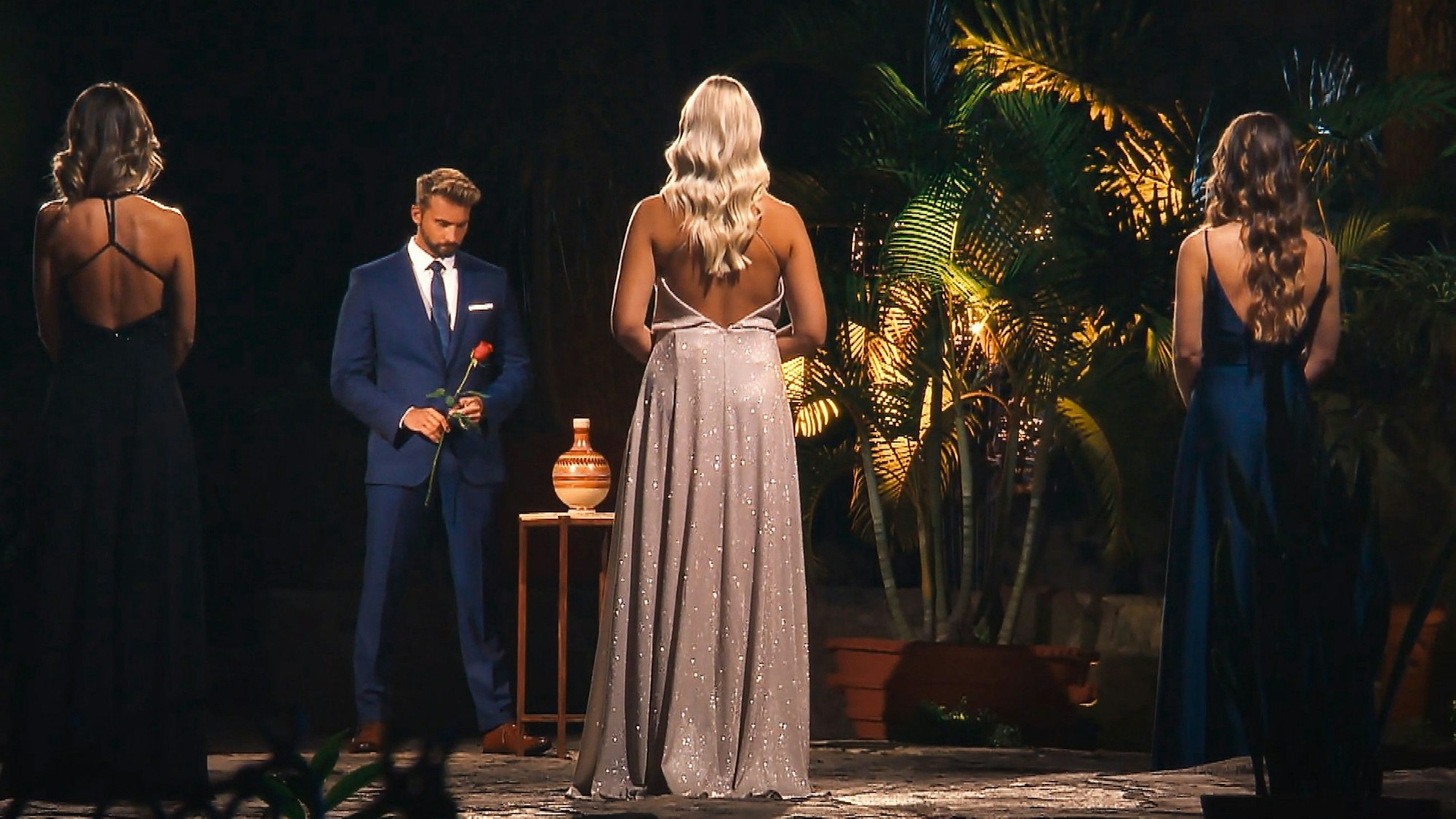 Bachelor Dominik Stuckmann steht mit einer roten Rose vor den drei letzten Frauen.
