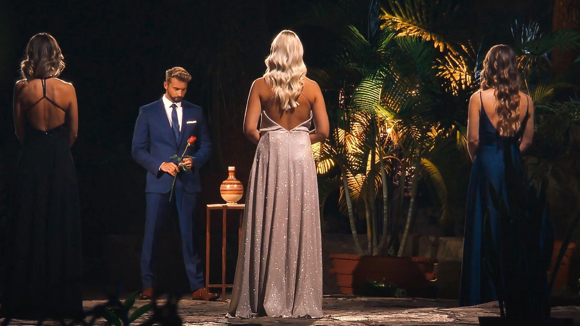 Bachelor Dominik Stuckmann steht mit einer roten Rose vor den drei letzten Frauen.