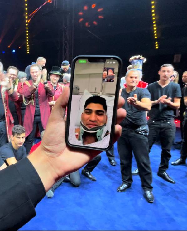 Ein Mann hält ein Handy in einer Hand, während er vor einer Gruppe steht.