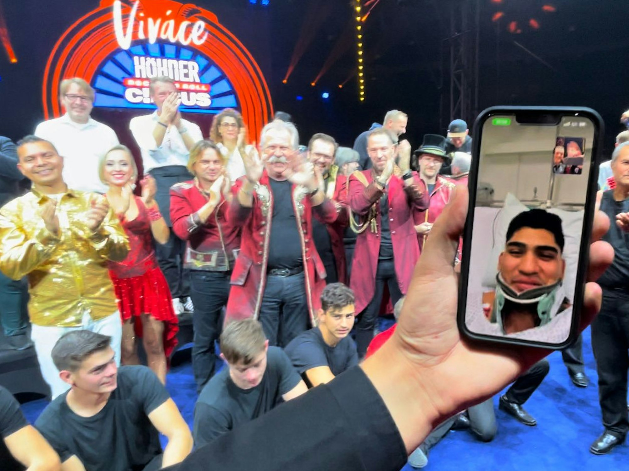 Ein Mann hält ein Handy in einer Hand, während er vor einer Gruppe steht.