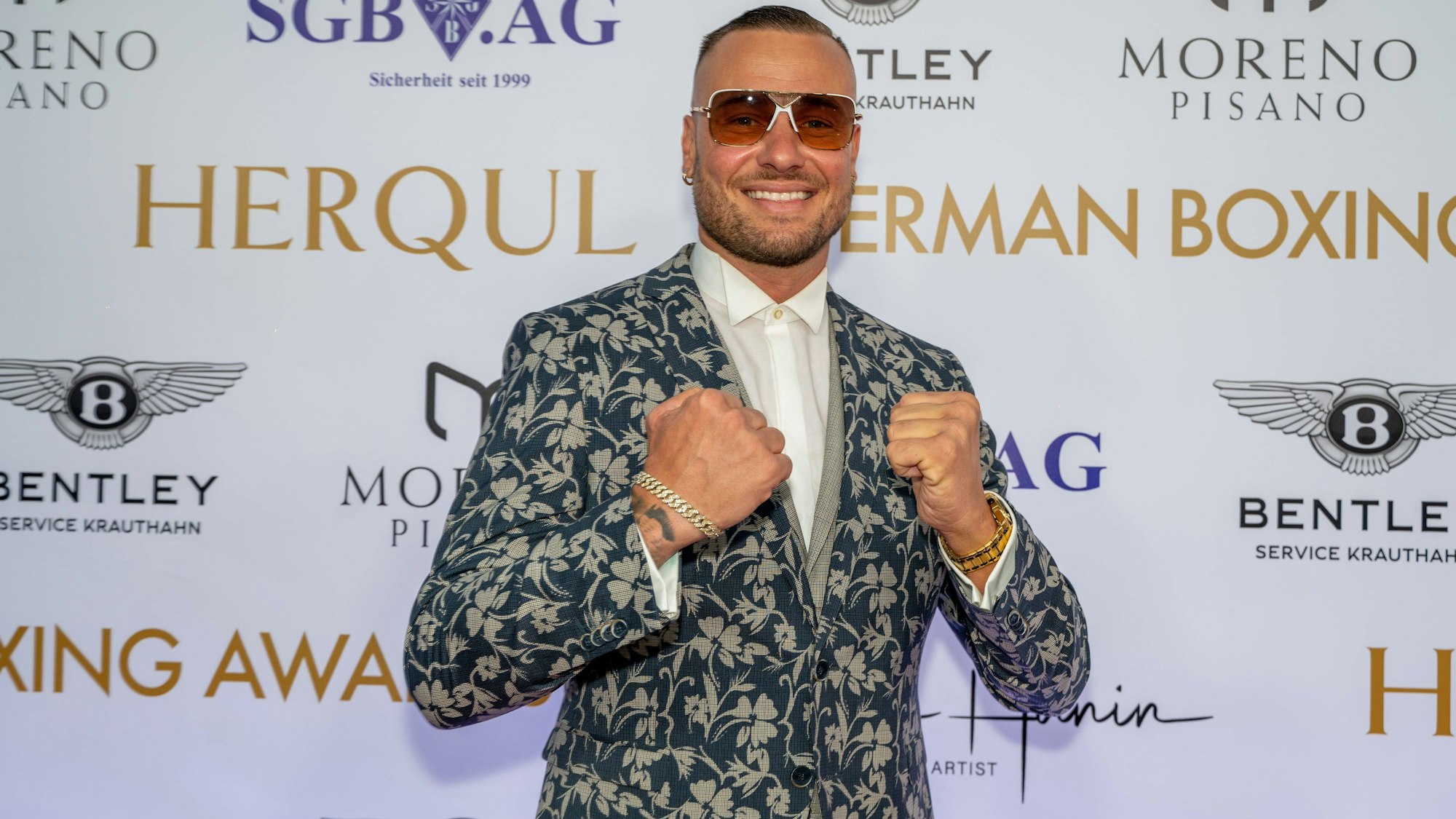 Eric Sindermann posiert in einem Blumenanzug für ein Foto. Er trägt eine Sonnenbrille mit rötlichen Gläsern.