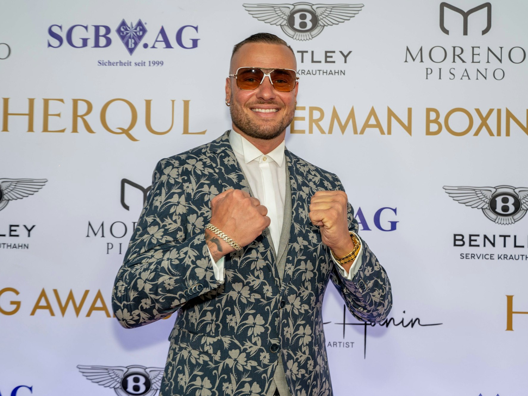 Das Foto zeigt Reality-Darsteller Eric Sindermann bei einer Preisverleihung in Berlin, wo er mit geballten Fäusten posiert.