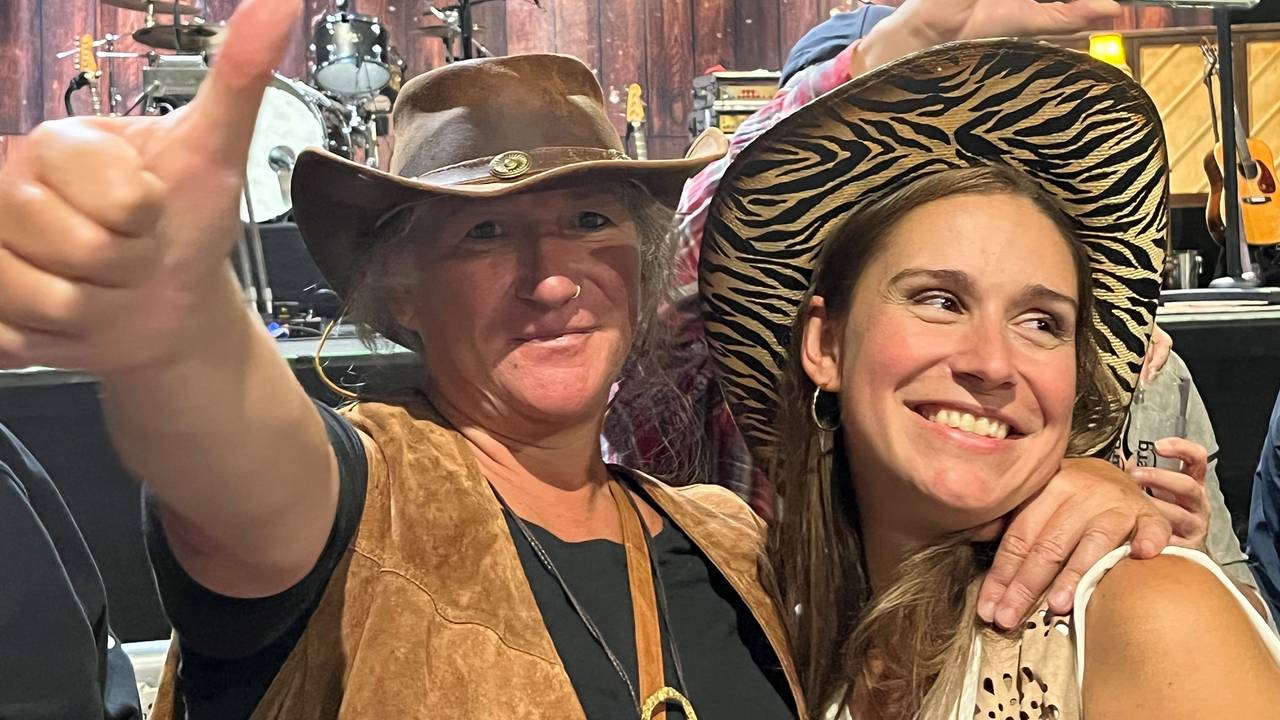 Zwei Frauen stehen bei einem Konzert vor der Bühne.