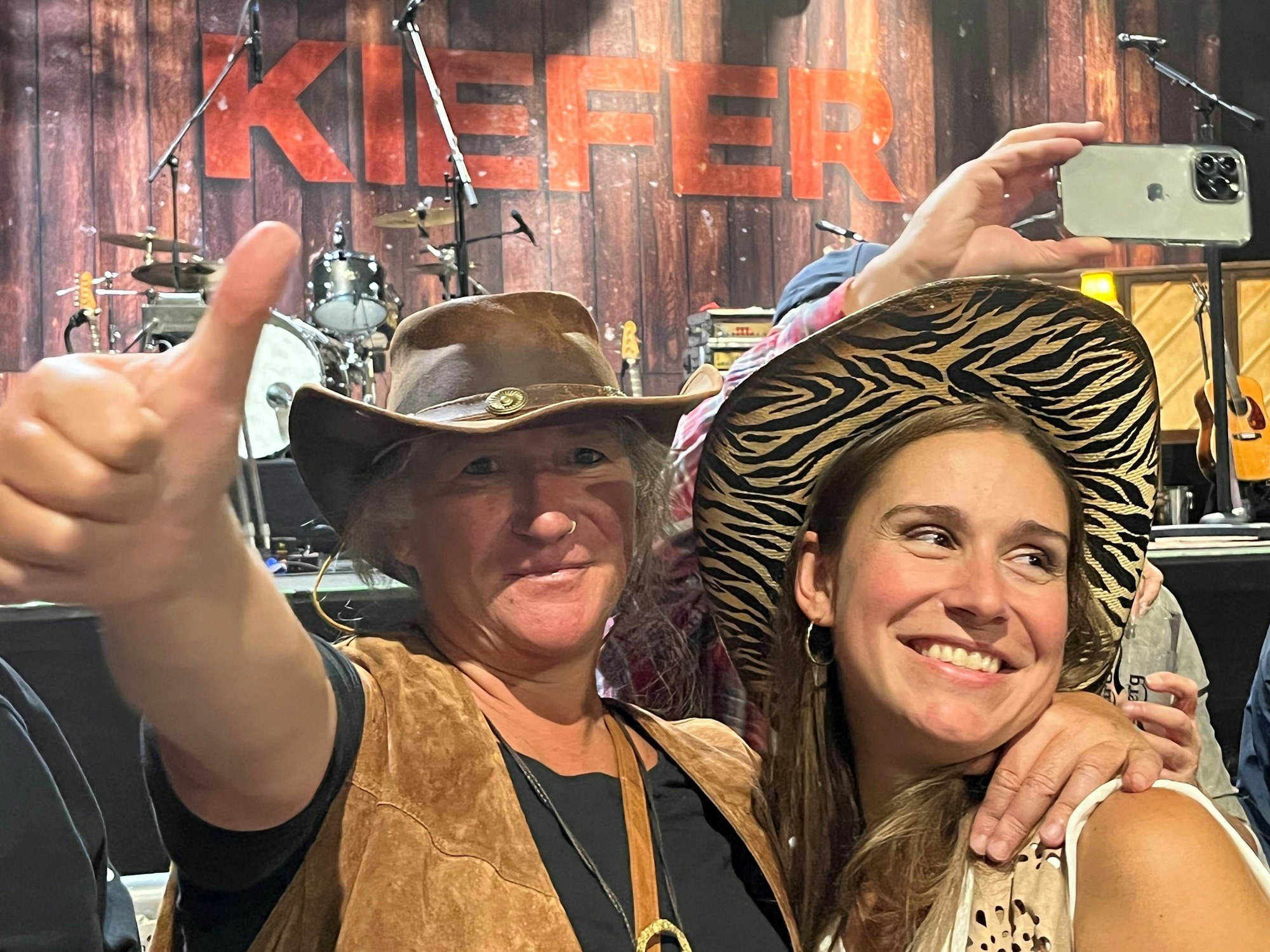 Zwei Frauen stehen bei einem Konzert vor der Bühne.