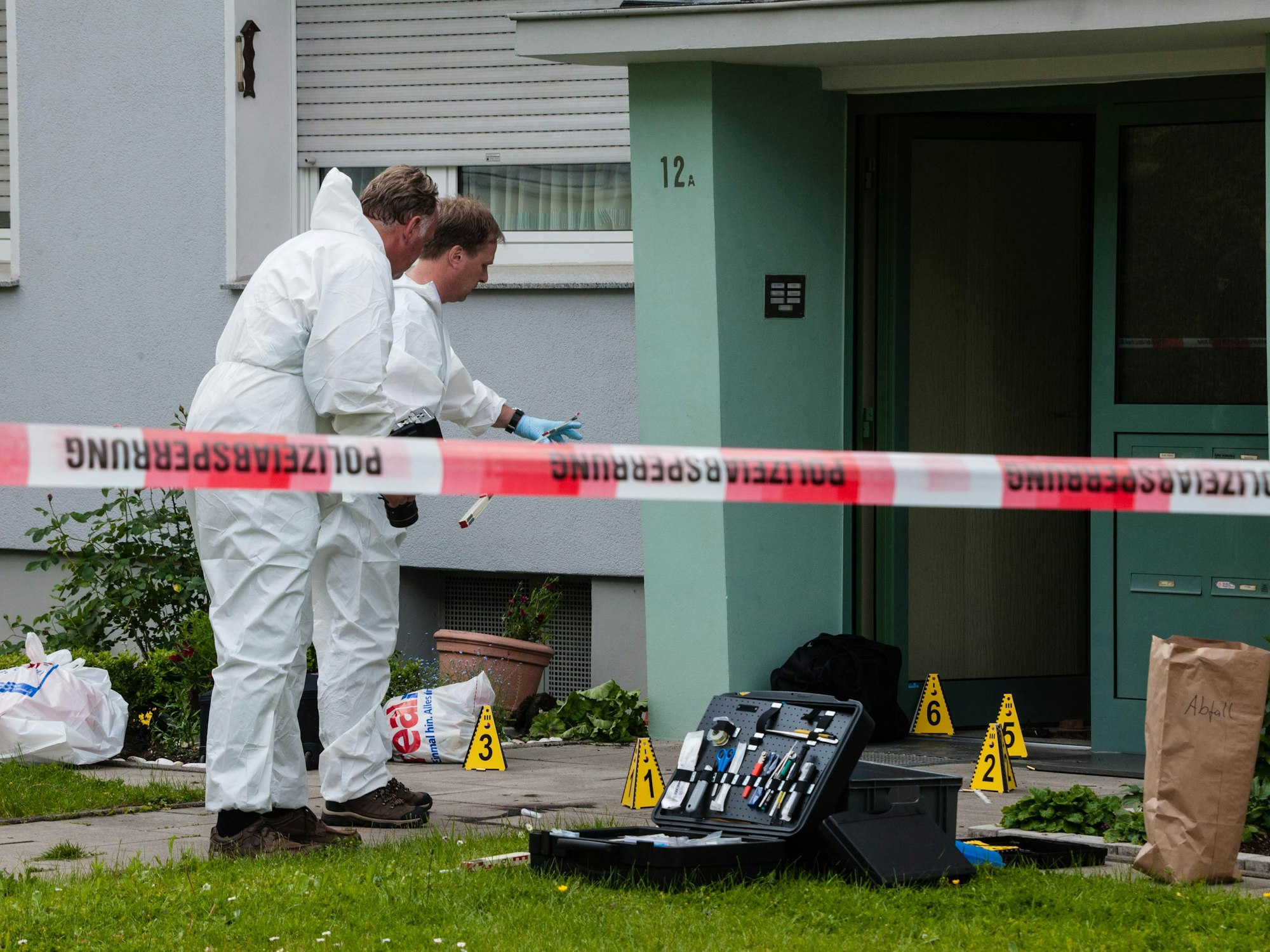 Beamte der Spurensicherung arbeiten vor einem Haus mit ihrem Equipment.