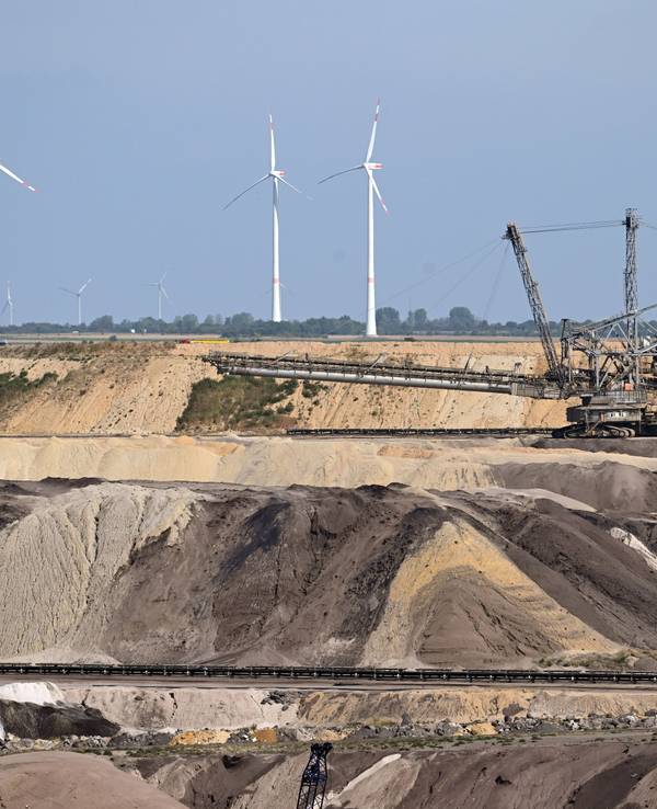 Ein Schaufelradbagger arbeitet im Braunkohletagebau Garzweiler. Im Hintergrund sind Windräder zu sehen. Das Foto stammt aus dem September 2022.